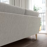 The GRILLSTORP sofa is a light gray, modern design with wooden legs. It stands out in a room with its sleek, inviting look and comfortable cushions.