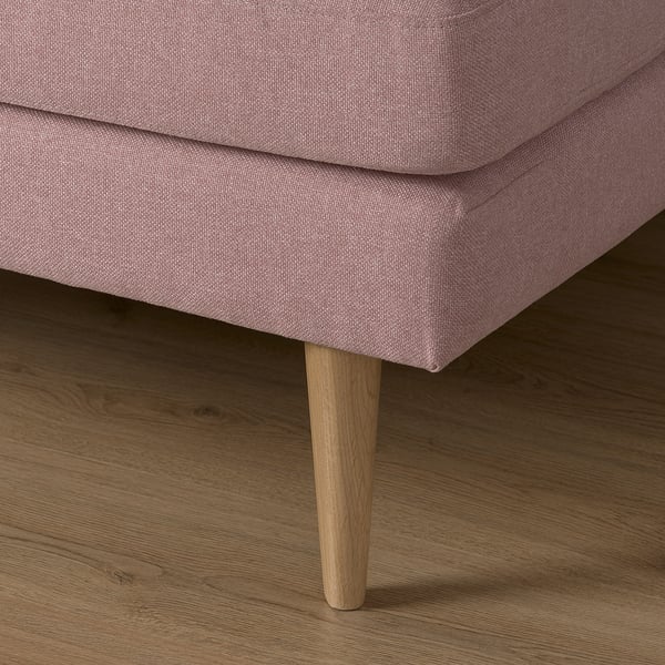 Close-up of pink upholstered sofa leg on wooden floor.