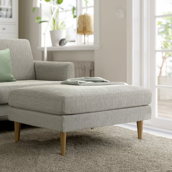 Mid-century GRILLSTORP sofa in tweed, light gray footstool, plants, lamp.