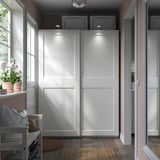 Modern room with white sliding GRIMO wardrobes on wooden floor.