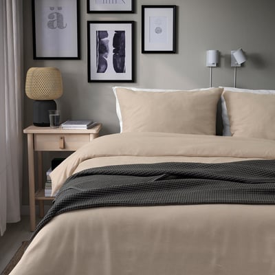 Beige GROVSNÄRJA duvet & pillows on bed, warm flannel, nightstand, lamp, wall art.
