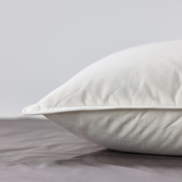 Close-up of a smooth, white pillow with plush, well-filled texture on a bed.