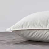 Close-up of a smooth, white pillow with plush, well-filled texture on a bed.