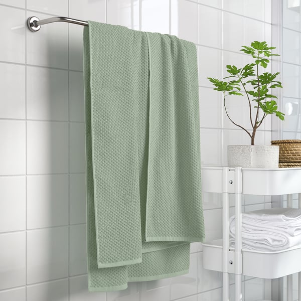 GULVIAL mint towel hangs near plant, showing soft, textured fabric. Size: larger than stack of white towels.