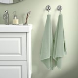Green towels hang near white sink with soap dispenser.