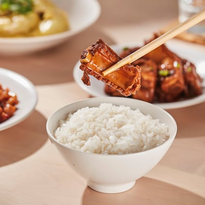 A meal of glazed meat and rice in small porcelain bowls, showcasing their stackable and lightweight design.