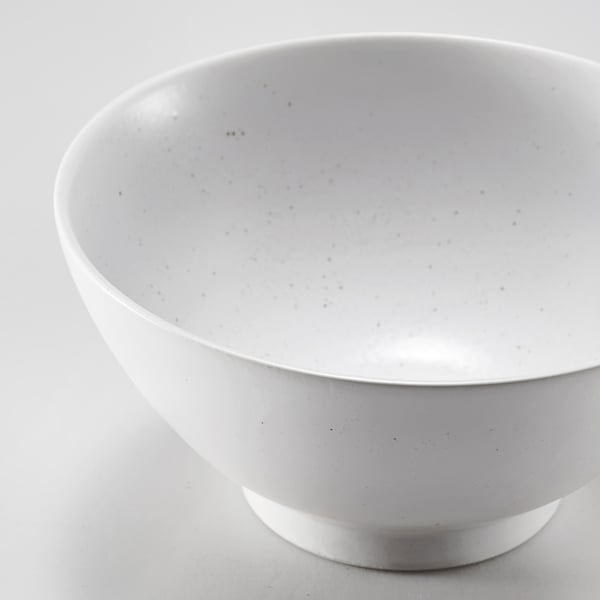 Round, white speckled bowl on a plain surface. Smooth, even glaze, light and durable.