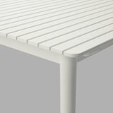 A close-up of a modern, white extendable dining table made from solid eucalyptus. The tables edge groove details, and the leg appears sturdy.