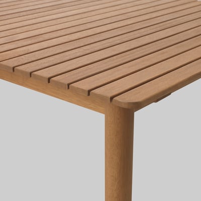 Close-up of HATTHOLMEN wooden table, showcasing smooth, polished eucalyptus wood with visible grain.