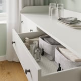 Organized white HAUGA chest drawer in kitchen. Contains bins with napkins, utensils, and containers. Clean, modern, and practical storage.