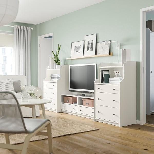 Modern living room with green walls, white HAUGA furniture, plants, and photos.