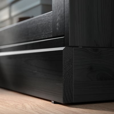 Black wooden furniture corner with sleek lines. Dark finish, smooth surface, and angled joint detail.