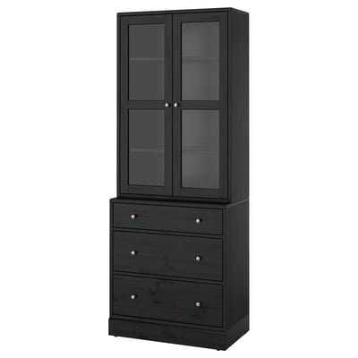 HAVSTA: tall black wooden cabinet with glass doors and three drawers, displaying rustic design.