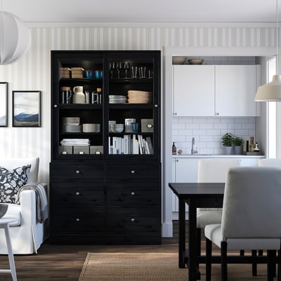 Modern living room with black HAVSTA cabinet, glass doors, white kitchen, couch, chairs, dining table.