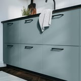 Modern turquoise HAVSTORP cabinet with sleek design and black handles, hanging white-striped towel.