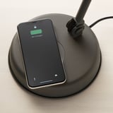A smartphone displays 98% charged on a wireless charging pad integrated into a vintage-style lamp.