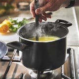 Hand stirring veggies on induction stove.