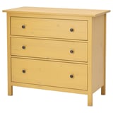 A HEMNES wooden chest of drawers in yellow, featuring three drawers with black knobs. Its rectangular with a simple, classic design.
