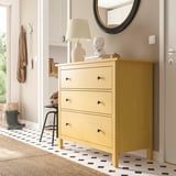 Bright yellow HEMNES chest with three drawers stands near a door, contrasting with white walls and patterned floor.