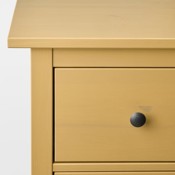 A close-up of a well-crafted mustard-yellow dresser with sleek drawer and knobs.