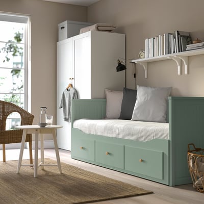 Modern small bedroom with HEMNES green day-bed, white wardrobe, and round table. Cozy, minimalist decor with soft lighting.