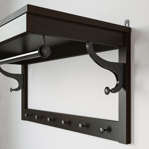Dark wood coat rack with multiple hooks and a shelf, ideal for hallways.