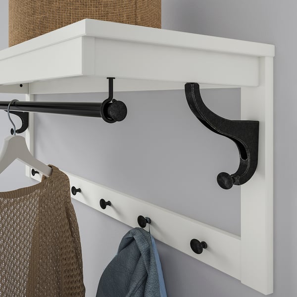 Wall-mounted coat rack with hooks and shelf for hanging clothes and accessories.