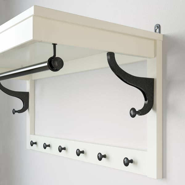 Wall-mounted coat rack with shelf, hooks, and clothes rail, white with black accessories, made of wood and metal.