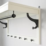 Wall-mounted coat rack with shelf, hooks, and clothes rail, white with black accessories, made of wood and metal.