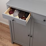 Gray wooden cabinet with open drawer displaying neatly folded ties, showcasing its storage and organization functionality.