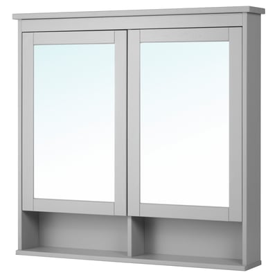 The HEMNES mirror cabinet is light grey, rectangular, with two mirrored doors and a tempered glass shelf.