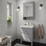 Modern grey bathroom with HEMNES vanity, mirror, towels, and plants. Sinks into clean, tiled walls.