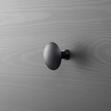 Dark metal wall-mounted hook on gray wooden surface.