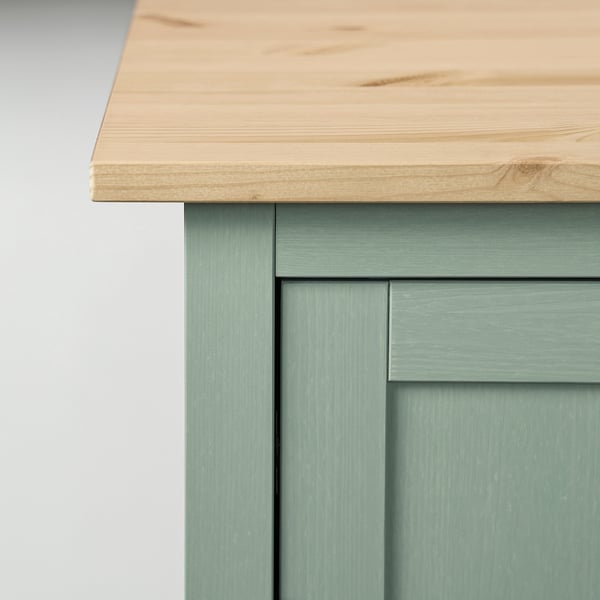 Wooden table top with smooth grain on green cabinet.
