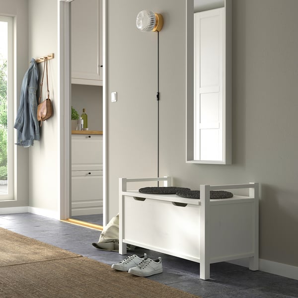 White HEMNES bench with shoe storage, large, beneath hanging lamp, near door, with jacket and bag on hooks.
