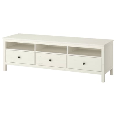 An ikea HEMNES white tv bench made of solid pine wood with three drawers and open compartments for storage.