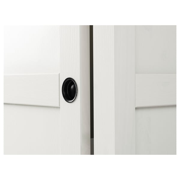 White wooden wardrobe with sleek, black circular handle. Protrudes minimalistic elegance, showcasing high-quality craftsmanship.