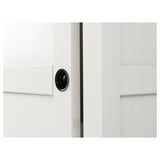 White wooden wardrobe with sleek, black circular handle. Protrudes minimalistic elegance, showcasing high-quality craftsmanship.