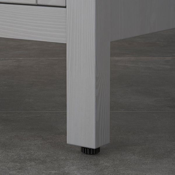 Close-up of wooden cabinet leg with adjustable foot, showcasing stability and moisture protection.