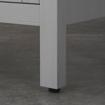 Close-up of wooden cabinet leg with adjustable foot, showcasing stability and moisture protection.