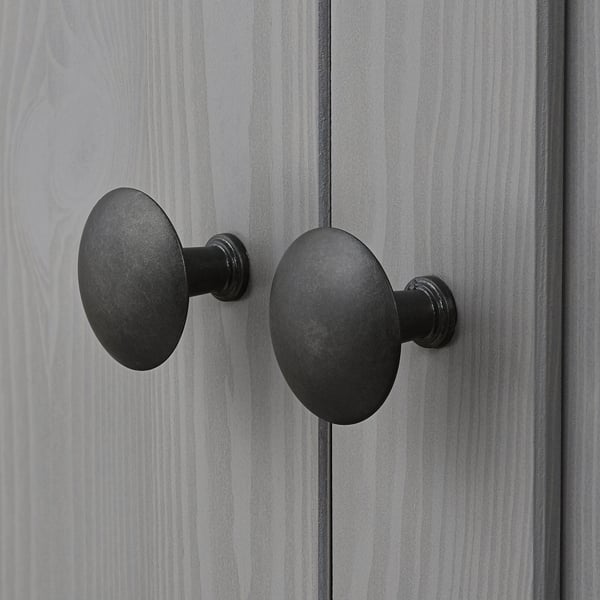 Dark-colored metal knobs affixed to a gray wooden surface, likely a cabinet door, showcasing a sleek and modern design.