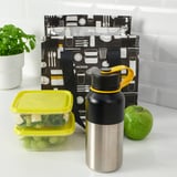 Insulated flask, grapes, greens, apple on counter