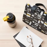 A stylish flask with a yellow loop, perfect for insulated drinks, fits in bags or car holders.