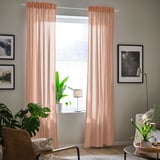 Peach curtains, plant, chair, lamp, picture in living room.