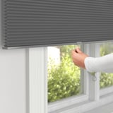 Hand adjusts window blind for light control and privacy.