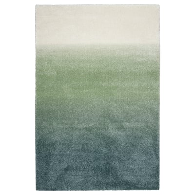 The HOTELLRUM rug with a gradient of blue, green, and white shades, rectangular shape, and soft texture.