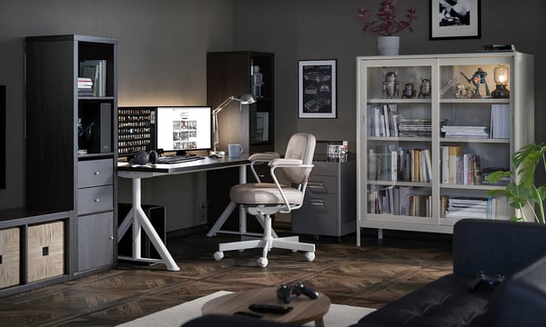 Modern home office with IDÅSEN desk, white chair, bookshelves, lamps, and monitor, designed for functionality and style.