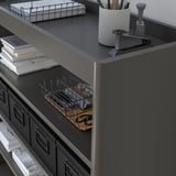 Black metal office shelf with wire baskets, paper stack, pen cup, and stapler. Elevated edges to prevent item fall.