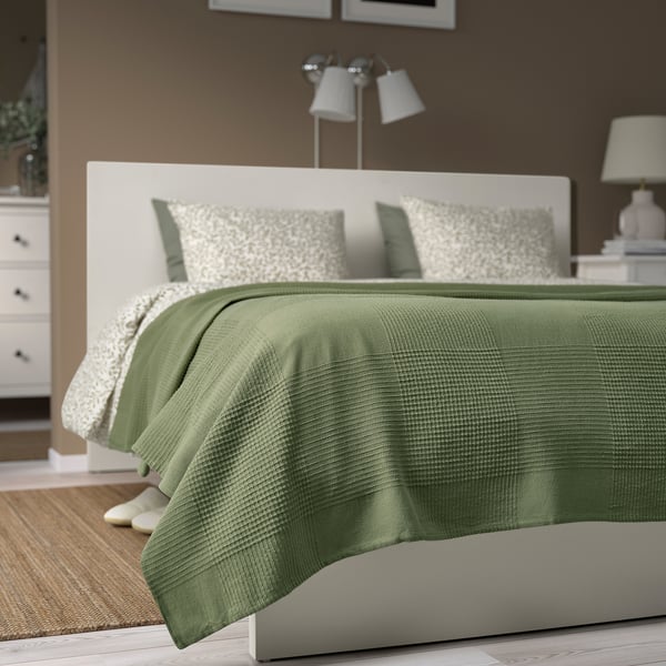 INDIRA bedspread: sage green, cotton, rectangular, layered on double bed. White accents, lamp above.