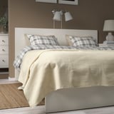 A cozy bedroom with an INDIRA off-white cotton bedspread on a double bed, flanked by nightstands and lamps.